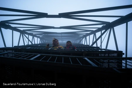 Zwei Wander schauen lachend im dichten Nebel vom Schombergturm nach unten