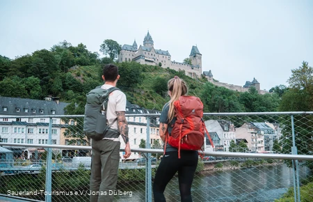 Zwei Wanderer blicken unten von der Lenne auf die Burg Altena