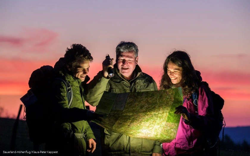 Der Ranger zeigt zwei Wanderern auf einer Karte den Weg