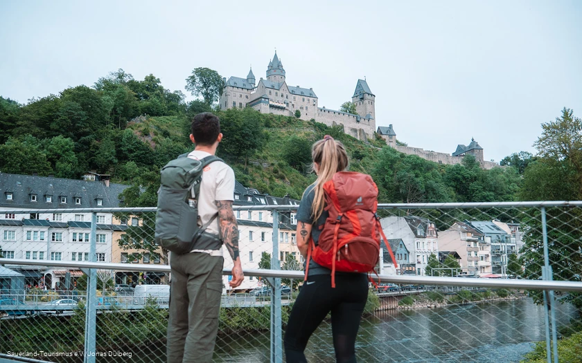 Zwei Wanderer blicken unten von der Lenne auf die Burg Altena