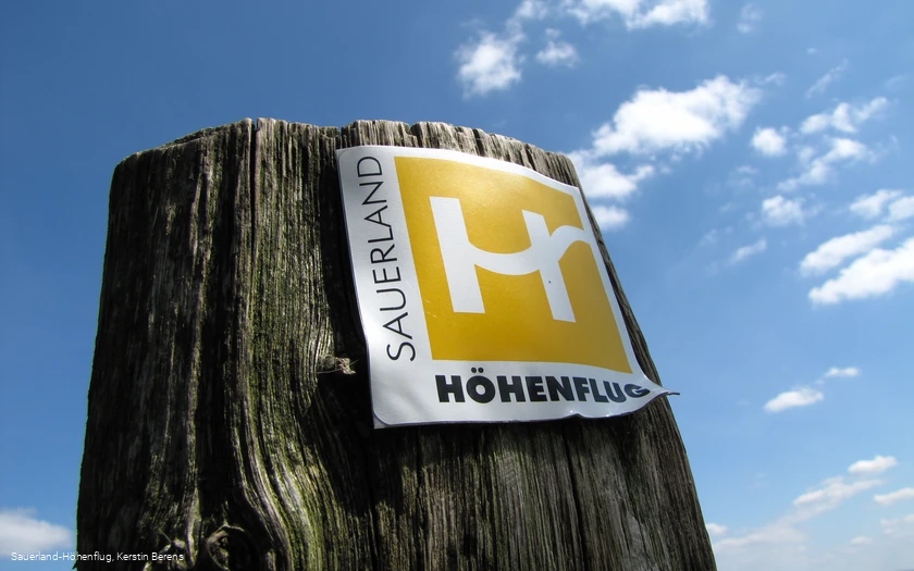 Markierungszeichen Sauerland-Höhenflug vor blauem Himmel