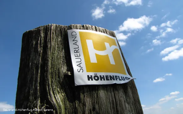 Markierungszeichen Sauerland-Höhenflug vor blauem Himmel