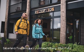 Zwei Wanderer starten ihre Wanderung am Hotel vor der Rezeption