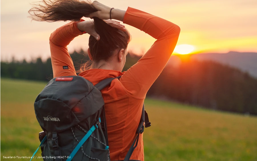 Eine Frau bindet sich einen Zopf bei Sonnenaufgang