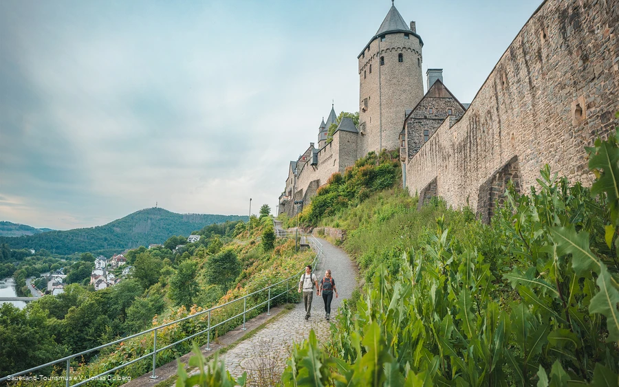 Zwei Wanderer wandern unterhalb der Burg Altena entlang