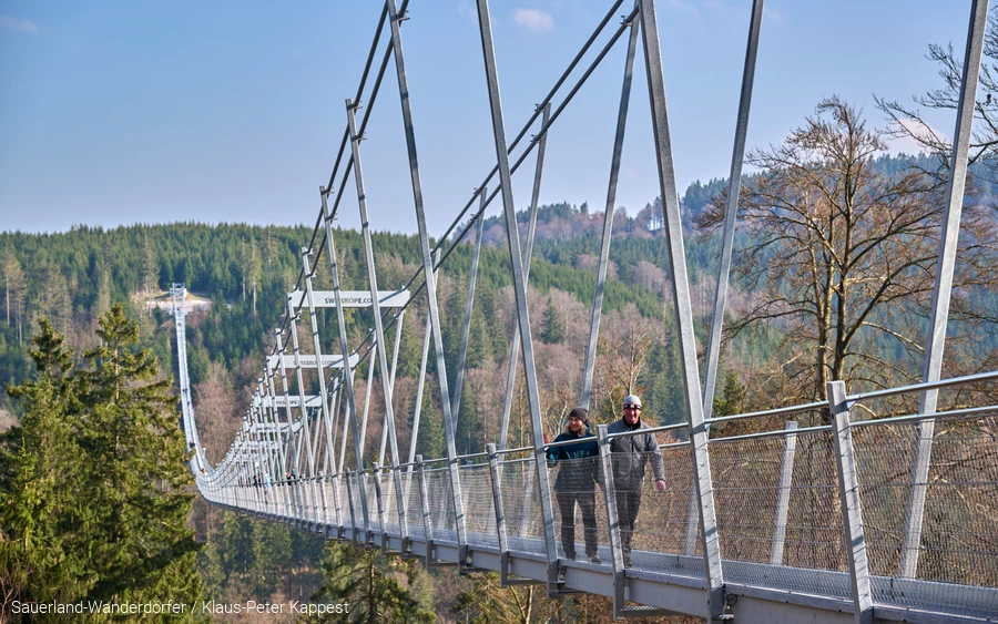Ein Paar läuft über eine Hängebrücke.