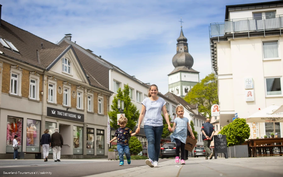 Eine Frau mit zwei Kindern geht fröhlich durch die Innenstadt von Attendorn