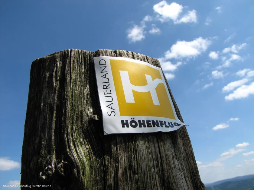 Markierungszeichen Sauerland-H&ouml;henflug vor blauem Himmel