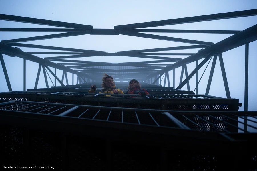 Zwei Wander schauen lachend im dichten Nebel vom Schombergturm nach unten