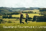Zwei junge Leute wandern oberhalb von Sundern-Hagen über eine Wiese