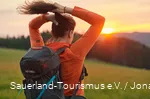 Eine Frau bindet sich einen Zopf bei Sonnenaufgang