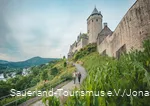 Zwei Wanderer wandern unterhalb der Burg Altena entlang