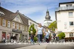 Eine Frau mit zwei Kindern geht fröhlich durch die Innenstadt von Attendorn