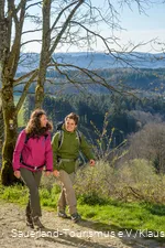 Zwei Wanderer wandern fröhlich nebeneinander oberhalb von Attendorn in Windhausen