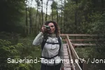 Eine Frau steht mit dem Fotoapperat auf einem Steg in den Ebbemooren