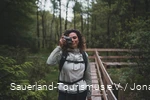 Eine Frau steht mit dem Fotoapperat auf einem Steg in den Ebbemooren