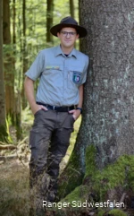 Ranger Torben Adler  neben einem Baum.