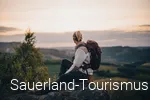 Frau sitzt auf einem Felsen und schaut in die Ferne.